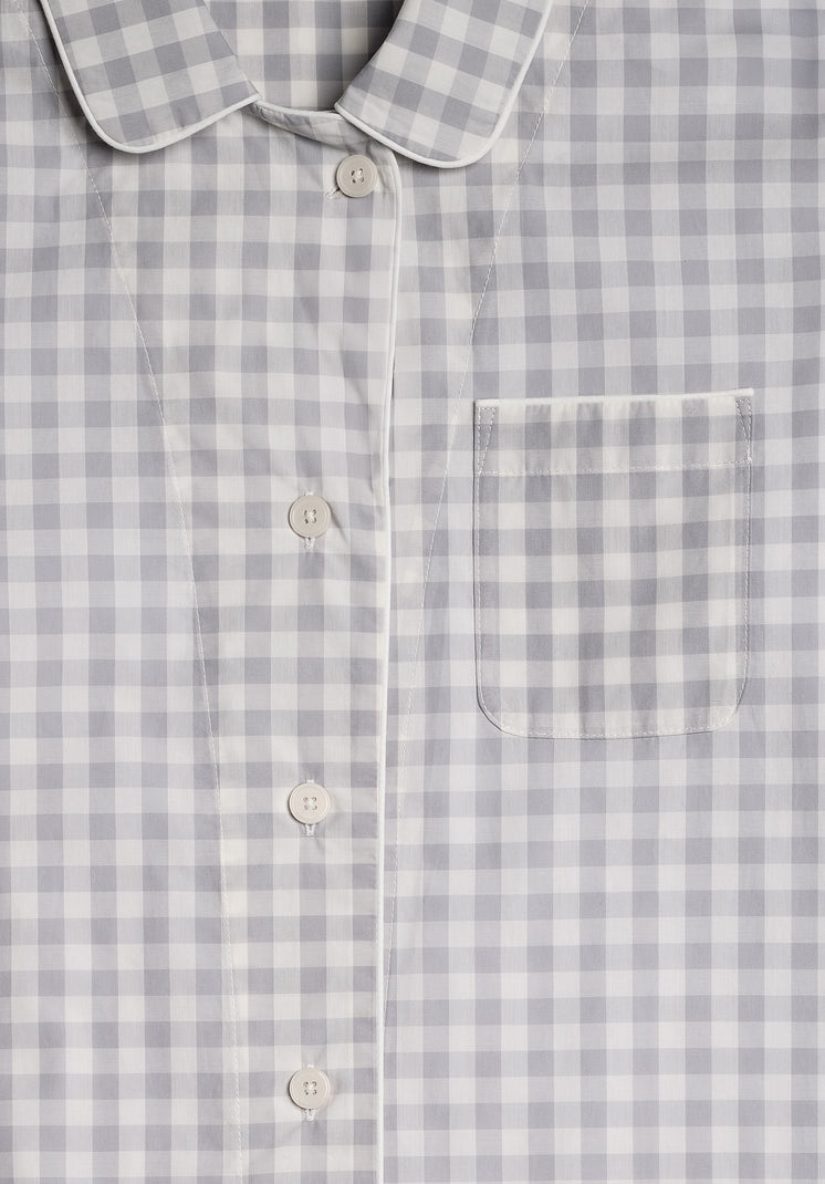 a close up photo of the collar detail, buttons, and chest pocket of a grey and white gingham pajama top
