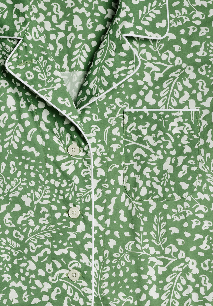 A detail of collar and chest pocket area of a green pajama shirt with a white botanical pattern.