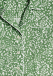 A detail of collar and chest pocket area of a green pajama shirt with a white botanical pattern.